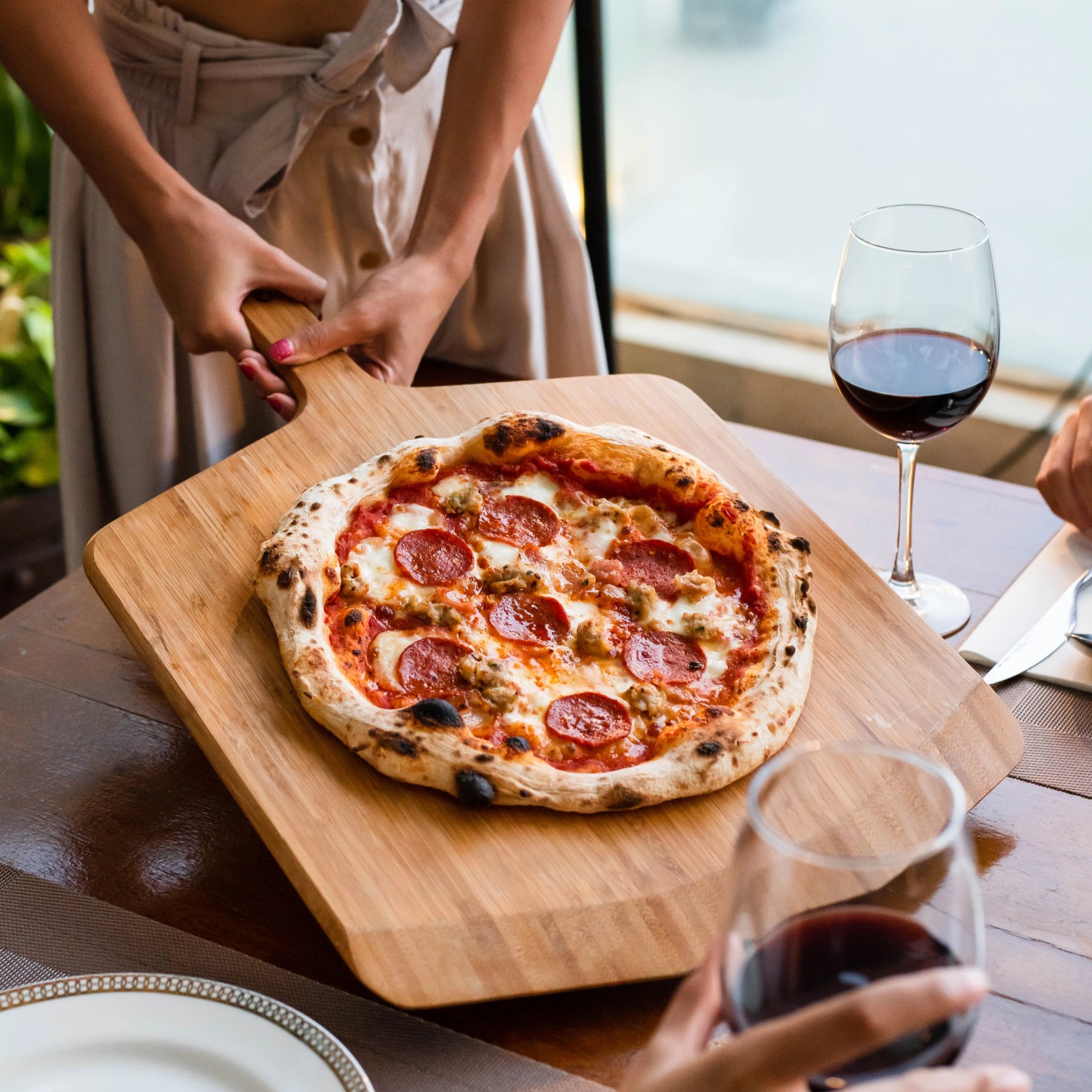 Ooni Pizzaschieber aus Bambus mit Pizza, auch als Servierbrett nutzbar.