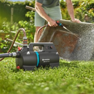 Gardena Akku-Gartenpumpe 3000 Silent 18V beim Bewässern einer Schubkarre im Garten.