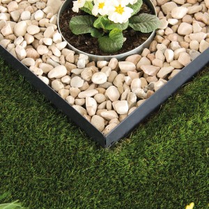 Bellissa Rasenkante in Anthrazit, eingefasst ein Beet mit Steinen und Blumen.