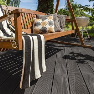 Anthrazitfarbene WPC-Terrassendielen Samana (4 m²) mit Holzmaserung auf Terrasse mit Gartenschaukel.