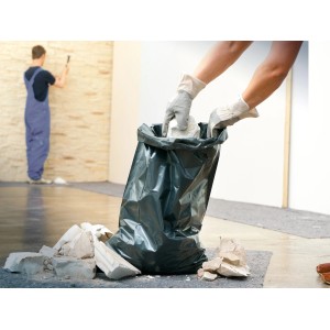 Schwarzer LUX Bauschuttsack 120l wird mit Bauschutt befüllt.