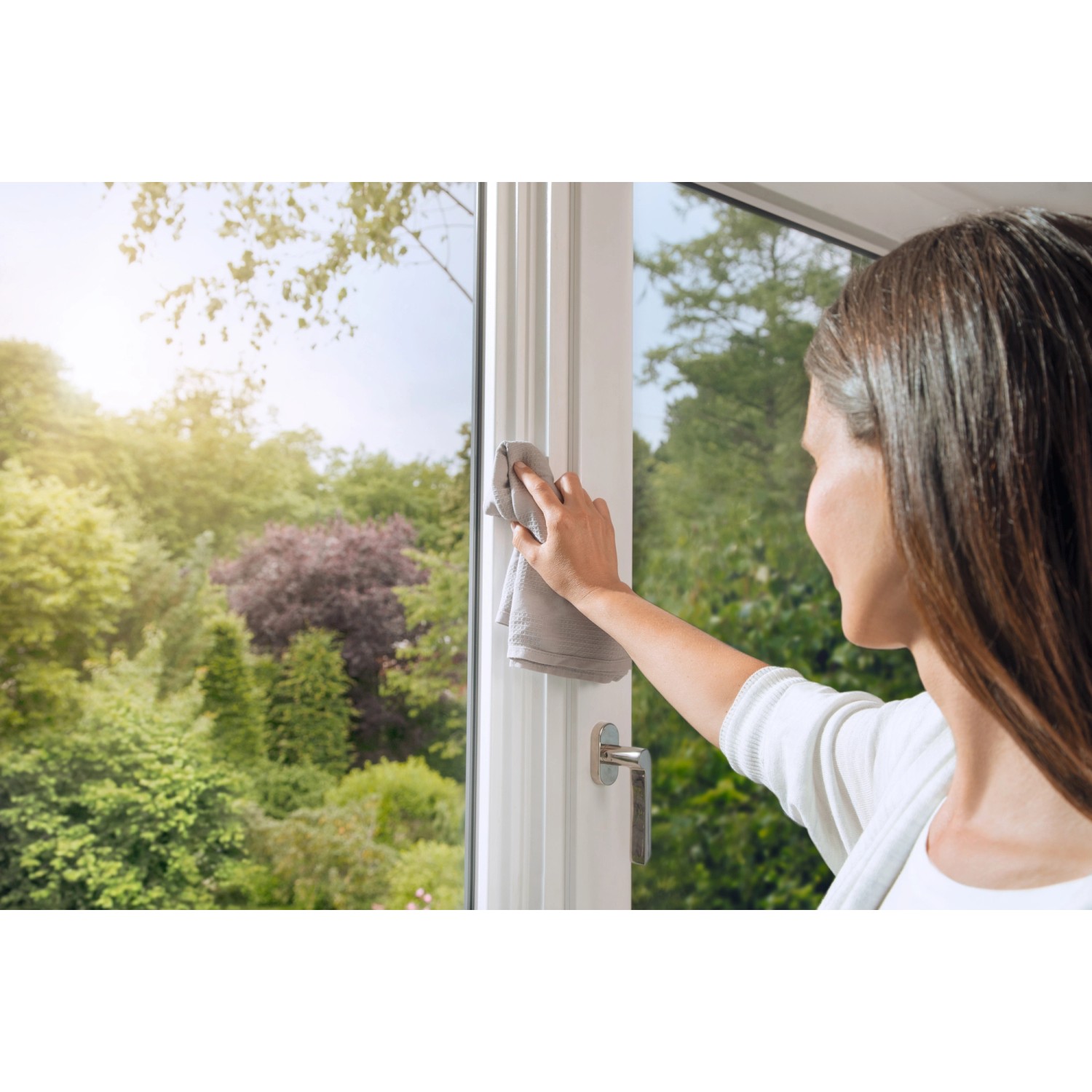 Frau reinigt Fensterrahmen vor der Montage eines Tesa Pollenschutzgitters.