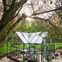 Halls Gewächshaus Garden Room, 12,9 m², grün, mit Glas und Aluminiumrahmen im Garten.
