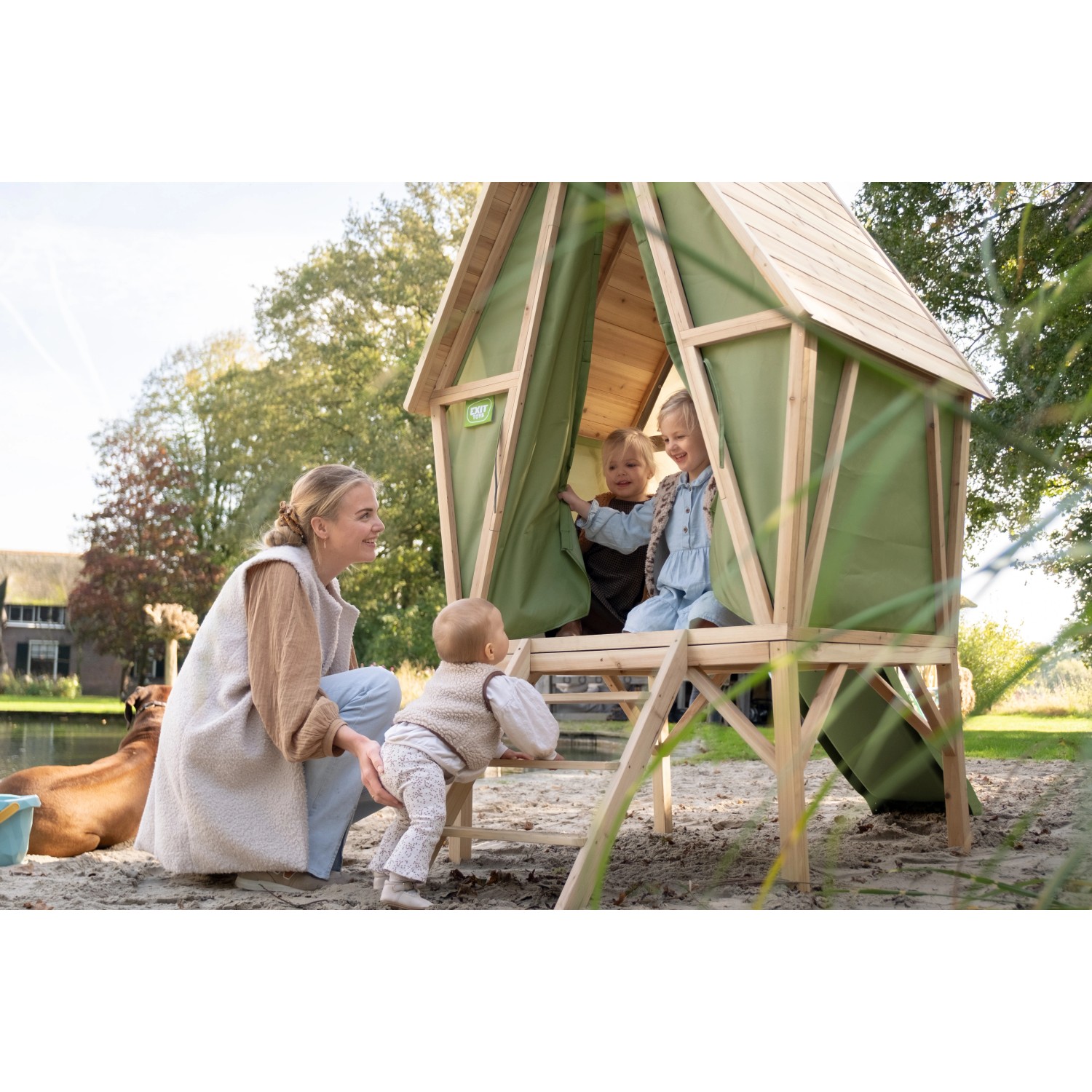 Exit Spielhaus Yuki 300 mit Rutsche: Holz-Spielhaus mit grüner Plane, Leiter und Rutsche. Kinder spielen.