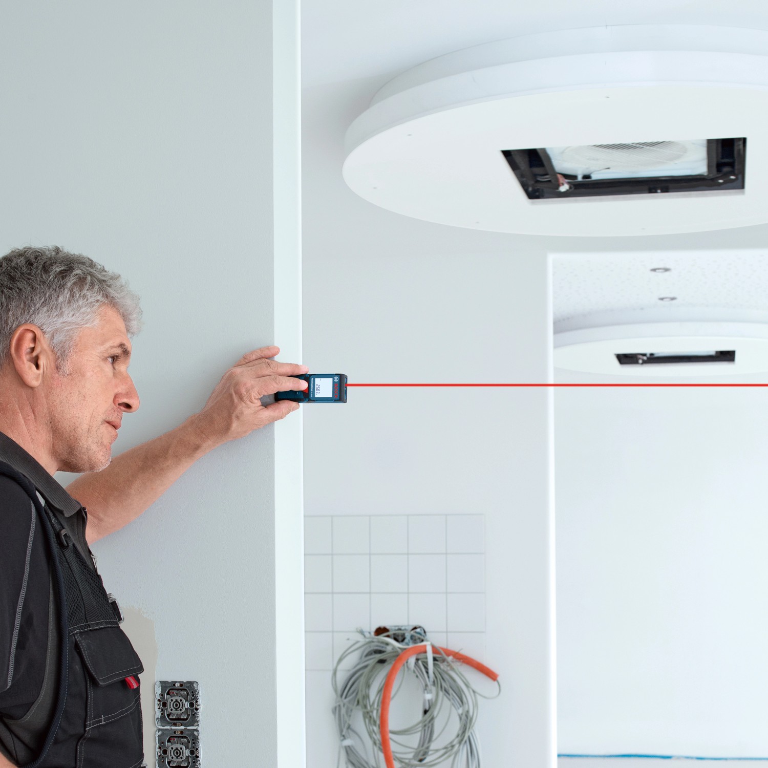 Handwerker misst mit Bosch Professional Laser-Entfernungsmesser GLM 40 digital einen Raum aus.