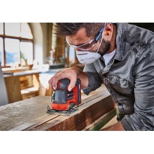 Einhell Akku-Faustschleifer TE-OS 18/113 beim Schleifen von Holz. Kompaktes Design, rot-schwarz.