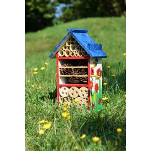 Bemaltes Insektenhotel-Bausatz für Kinder aus Holz mit Füllmaterial im Garten.