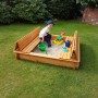 Holz Sandkasten Donald 140x140 cm mit klappbarer Abdeckung als Sitzbank und spielendem Kind.