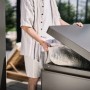 Person verstaut Kissen in dunkelgrauer Biohort Loungebox 160. Ideal für Sitzkissen und Gartenzubehör auf der Terrasse.