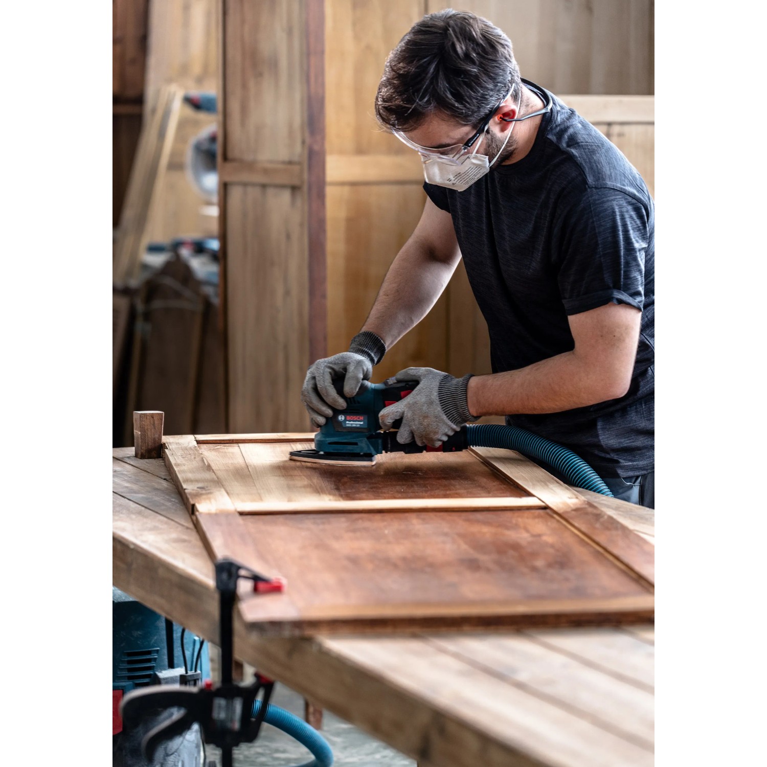 Mann schleift Holz mit Bosch Schwingschleifer und Expert Netzschleifblatt M480.