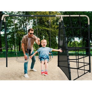 AXI Spielplatz mit Doppelschaukel und Klettergerüst in Anthrazit/Creme mit Kind auf Schaukel.