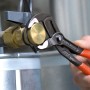 Knipex Cobra Rohrzange 300 mm im Einsatz an einem Ventil. Die Zange ist grau atramentiert und hat orangefarbene Griffe.
