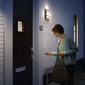 Frau vor Haustür mit Philips LED Außenwandleuchte Petronia mit Bewegungssensor in Anthrazit.
