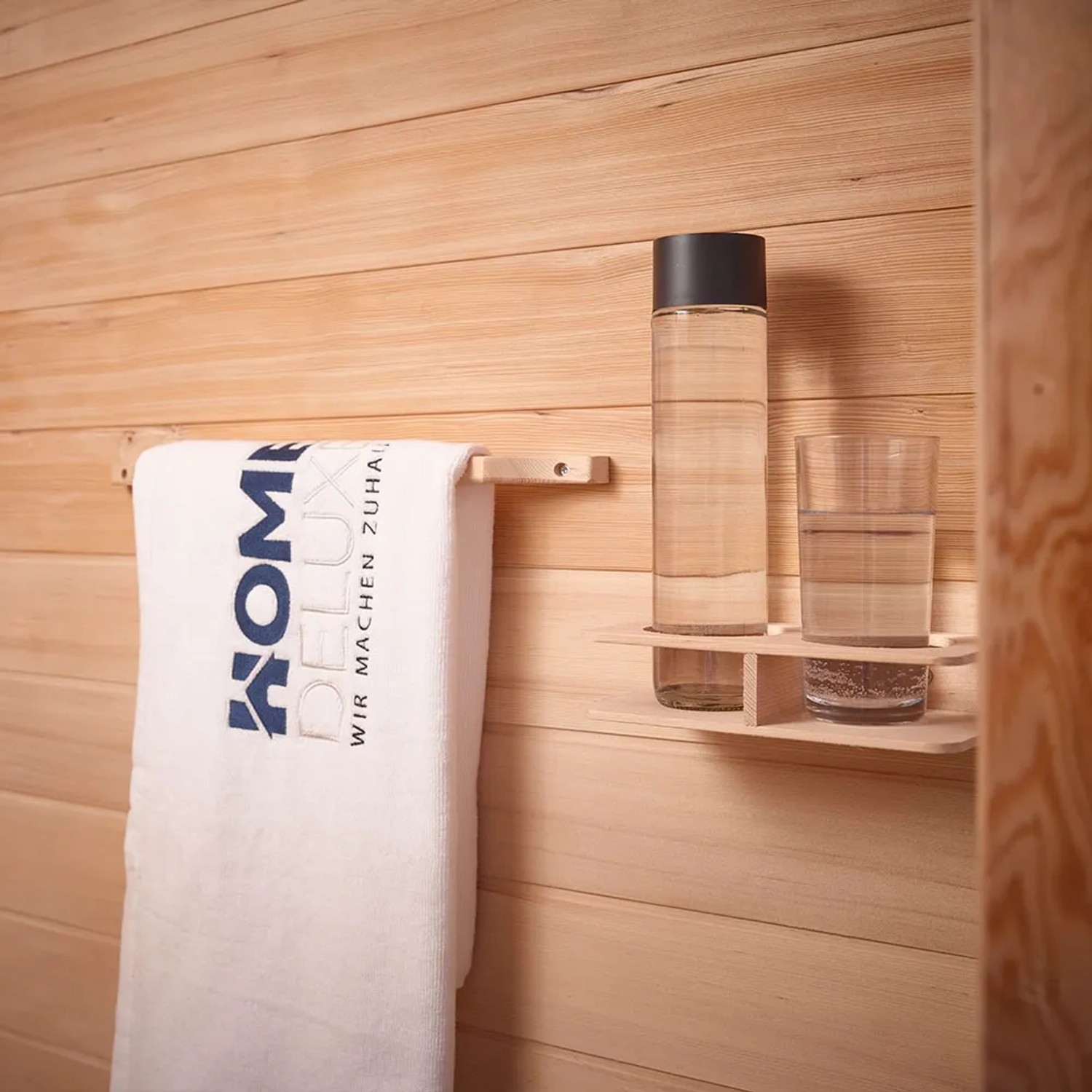 Detailaufnahme: Handtuch, Wasserflasche und Glas in Redsun Deluxe Infrarotkabine aus Tannenholz.