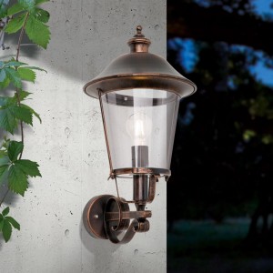 Orion Außen Wandleuchte Schwarz-Kupfer, rustikale Laternenform mit klarem Glas, an Betonwand. Ideal für Garten & Terrasse.