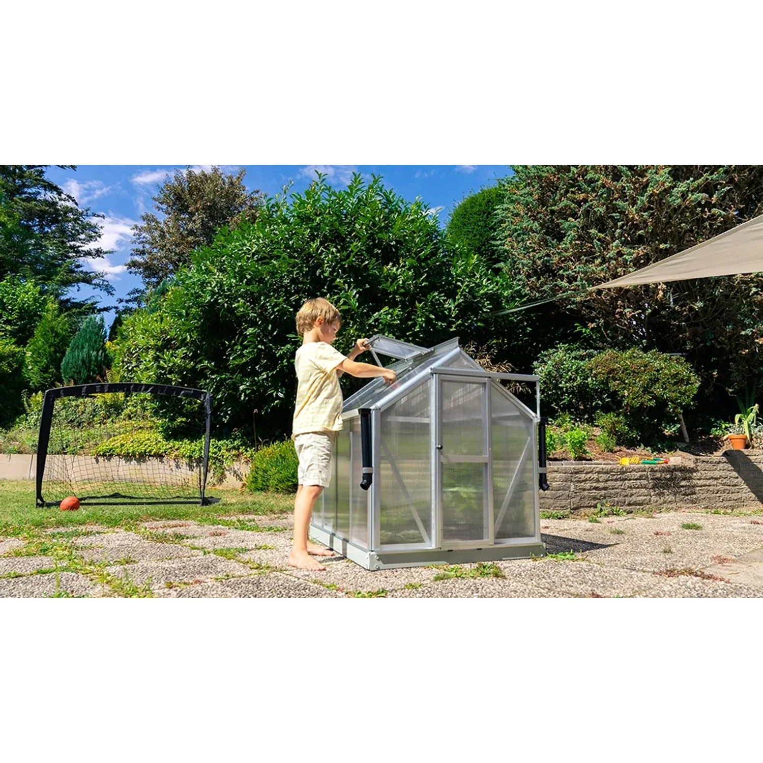 Vitavia Minigewächshaus Merlin mit Kind im Garten. Kleines Gewächshaus aus Aluminium mit Hohlkammerplatten.