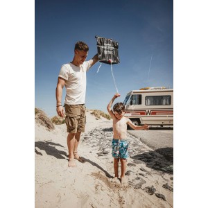 Enders Solardusche 20 l im Einsatz: Vater duscht Kind am Strand, Camping im Hintergrund.
