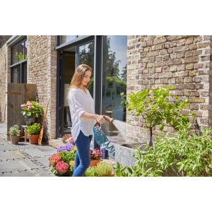 Frau bewässert Pflanzen mit Gardena Spiralschlauch-Set (10 m) im Garten.