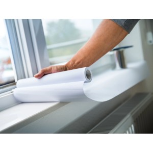 Weiße LUX Abdeckpapier Rolle (0,3 m x 10 m) wird auf einer Fensterbank ausgerollt.
