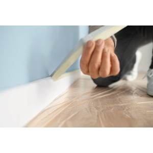 Anwendung von Tesa Malerband Classic (50mm) zum Abkleben einer Fußleiste vor dem Streichen.