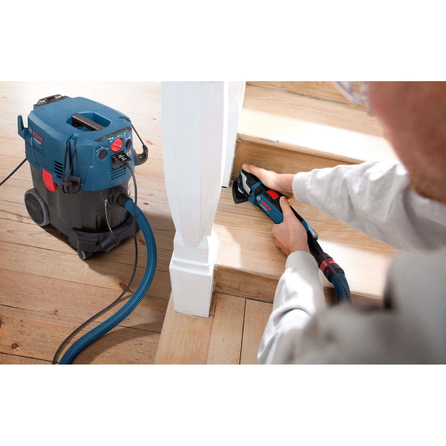 Bosch Professional GAS 35 M AFC Industriestaubsauger mit Schlauch im Einsatz beim Schleifen einer Treppe.