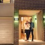LEDVANCE Smart+ Brick Außenleuchte in Silber an einer Hauswand mit Paar vor der Haustür.