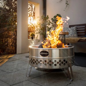 Petromax Feuerschale Tyropit aus Edelstahl mit Feuer und Lagerfeueratmosphäre im Garten.