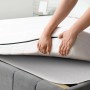 Person legt Beautissu Matratzenschoner mit Noppen unter Matratze. Rutschfester Nadelfilzschoner schützt vor Abnutzung.