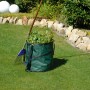 Grüner Gartensack Pop Up (85 l) mit Gartenabfällen und Rechen auf Rasen.