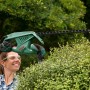 Frau schneidet Hecke mit Bosch Elektro-Heckenschere EasyHedgeCut 45. Das Gerät ist grün und schwarz.