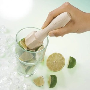 Fackelmann Zitronenstößel aus Holz beim Zerdrücken von Limetten in einem Glas.