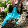 Gardena Blumenkelle Classic im Einsatz: Hand hält Kelle mit Erde im Gartenbeet.