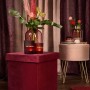 Rosa Sitzhocker Blush Bordeaux mit Stauraum und goldenen Akzenten vor Vorhängen.