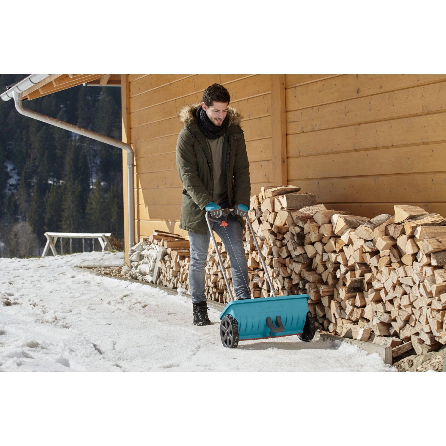 Mann nutzt Gardena Streuwagen L im Winter zum Streuen von Salz auf einer verschneiten Fläche.