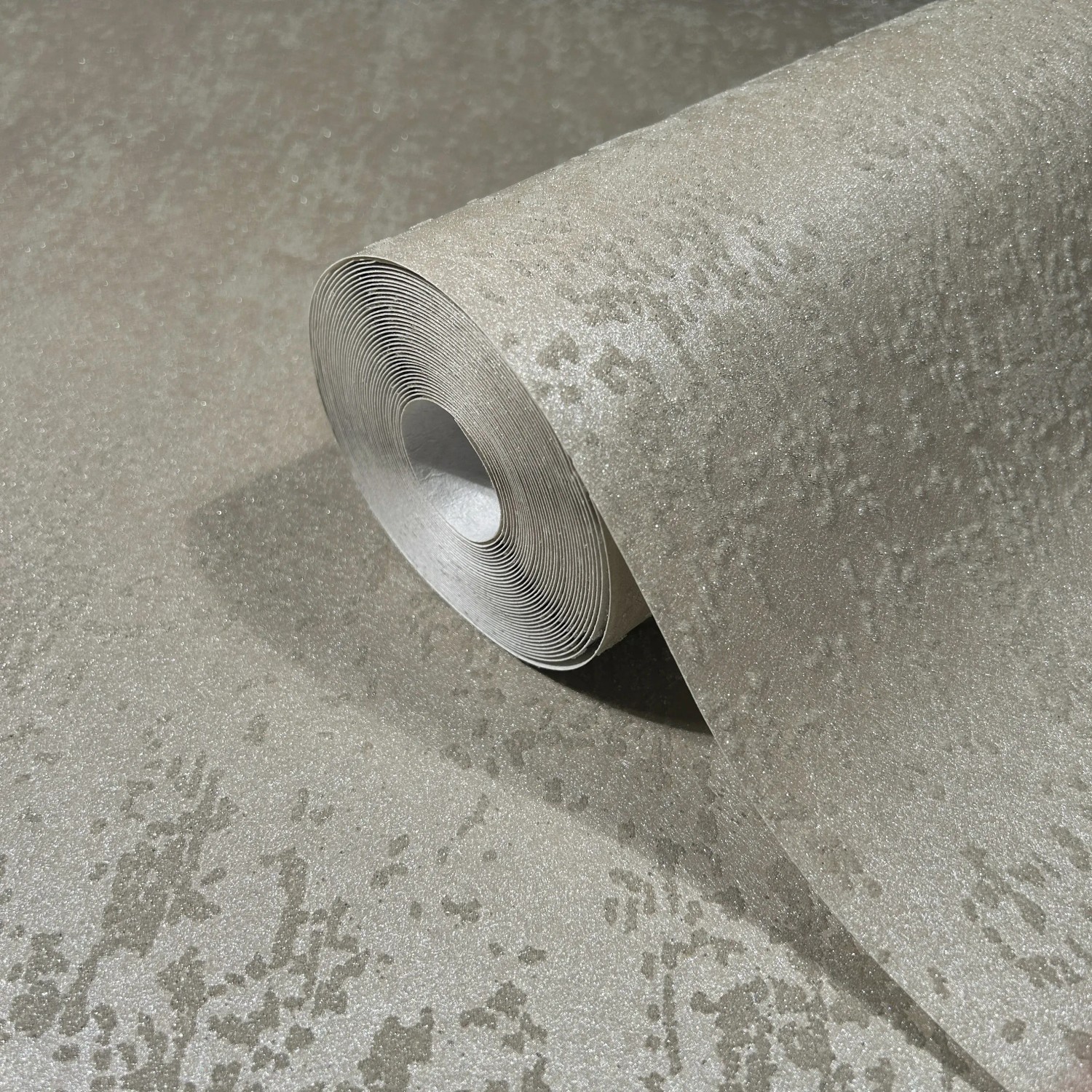 Beige Vliestapete mit Glitzer und Metalloptik von Marburg, Rolle teilweise aufgerollt.