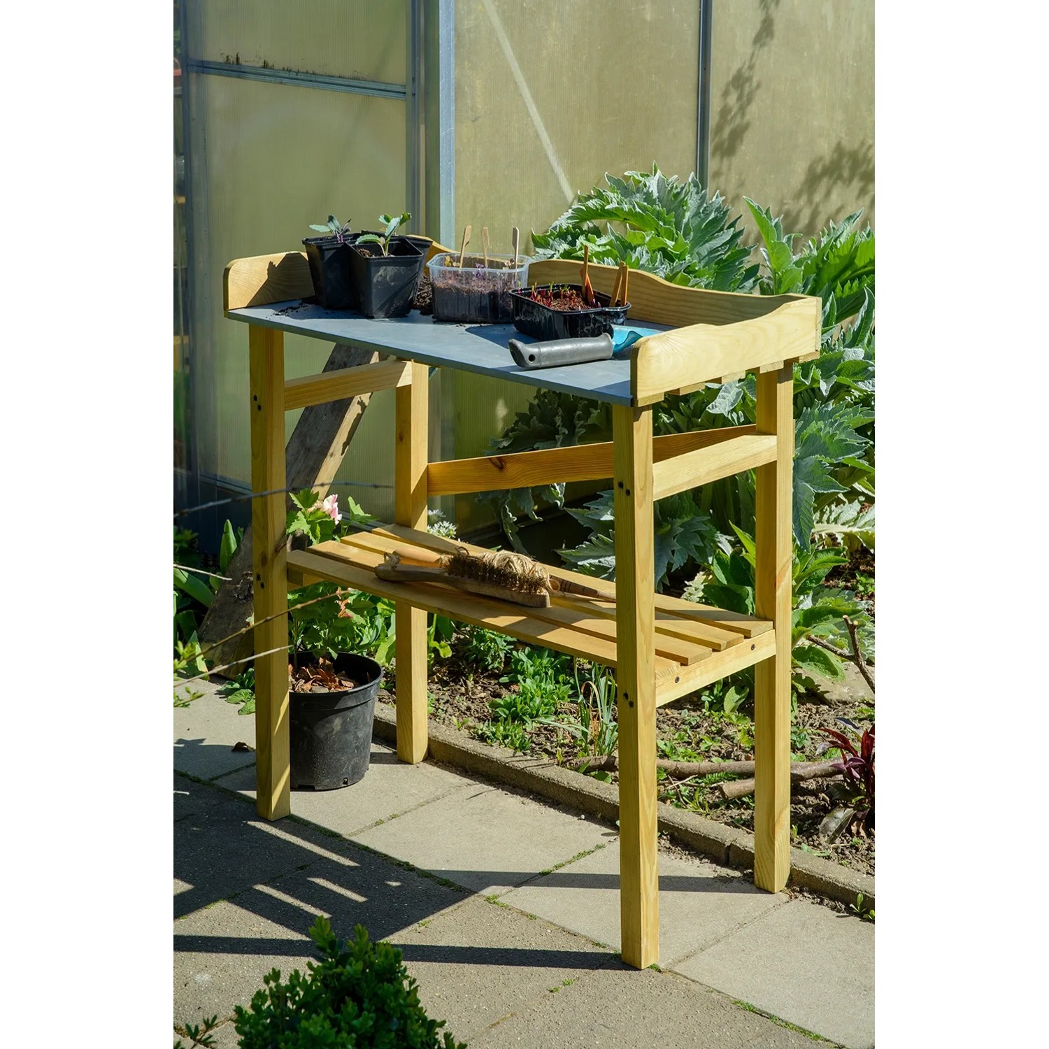 Robuster Pflanztisch aus imprägniertem Kiefernholz mit Ablagefläche und Gartenzubehör.