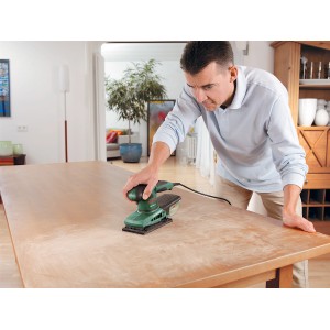 Mann schleift Tisch mit Bosch Schwingschleifer PSS 200 A. Schleifmaschine mit Micro-Filtersystem im Einsatz.