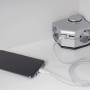 Winkeltischsteckdose mit 2 Steckdosen, 2 USB-Ports und Smartphone beim Laden.