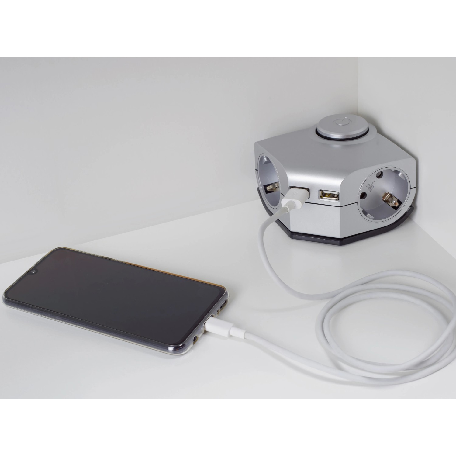 Winkeltischsteckdose mit 2 Steckdosen, 2 USB-Ports und Smartphone beim Laden.