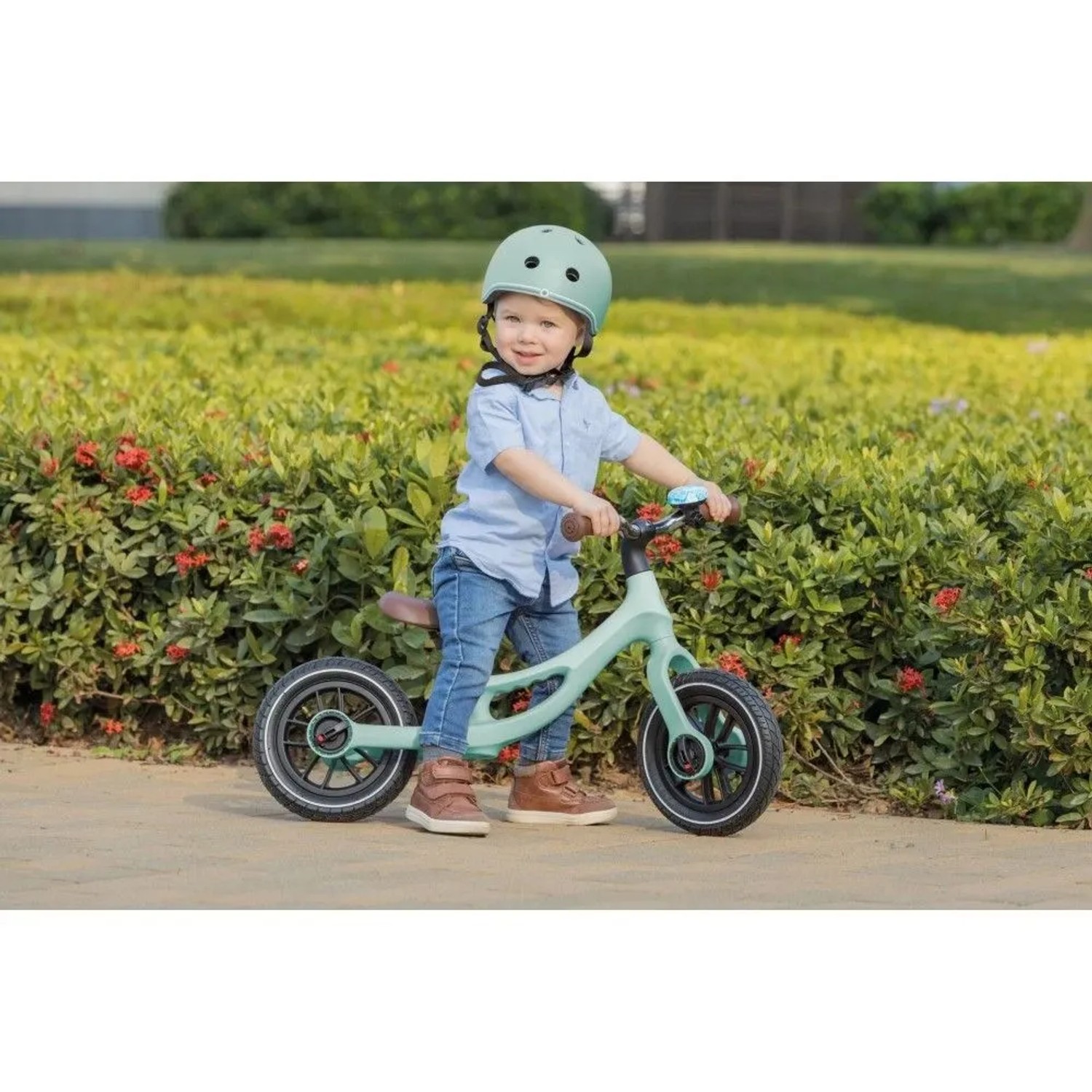 Lachendes Kind auf mintgrünem Globber Go Bike Elite Air Laufrad mit 10 Zoll Luftbereifung. Höhenverstellbarer Sattel.