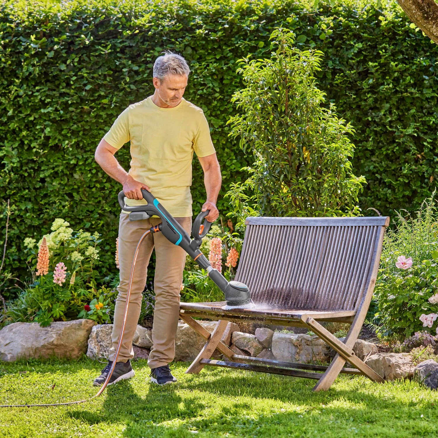 Mann reinigt Holzbank mit Gardena Akku-Multi-Reiniger AquaBrush. Inkl. Akku.