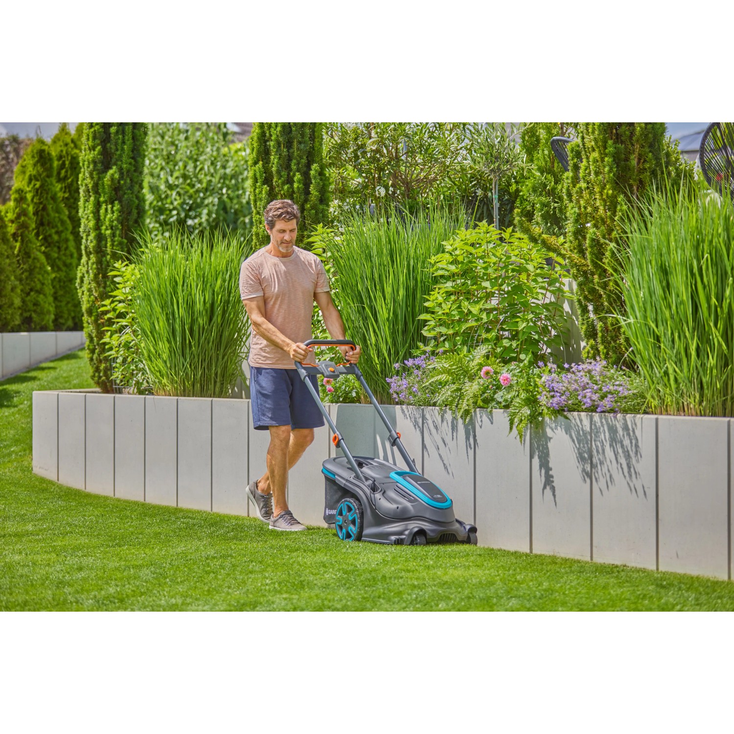 Mann mäht Rasen mit Gardena Akku-Rasenmäher PowerMax Duo 46/36 V. Rasenpflege im Garten.