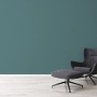A.S. Création Vliestapete Uni Petrol an Wand, kombiniert mit Sessel und Hocker.