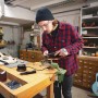 Mann schleift Werkstück mit Worx MakerX Mini-Winkelschleifer in Werkstatt. Akku-Winkelschleifer mit HubX.