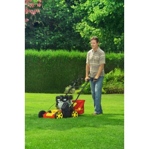 Mann vertikutiert Rasen mit Wolf-Garten Benzin-Vertikutierer VA 357 B. Elektro-Vertikutierer in Aktion.