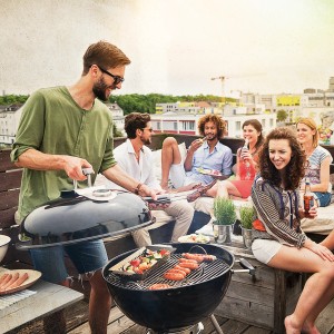 Jamestown Holzkohle-Kugelgrill Dexter XL beim Grillen mit Freunden auf einer Dachterrasse.