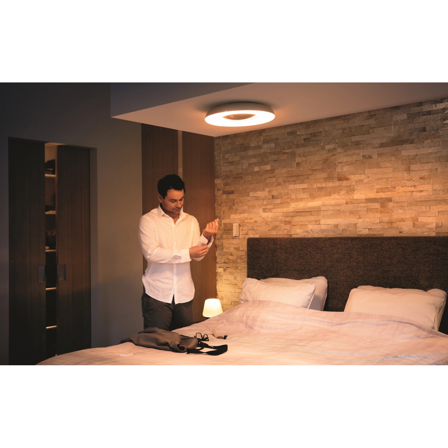 Schwarze Philips Hue Deckenleuchte White Ambiance Still im Schlafzimmer mit Mann.