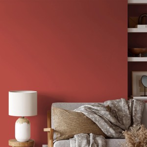 Wand in Ziegelrot mit V&CO Premium-Innenfarbe Dead Flat Matt. Wohnraum-Szene mit Sofa und Lampe.
