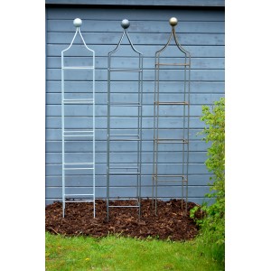 Drei unbeschichtete Eleo Obelisk Catania Rankhilfen in verschiedenen Farben im Garten.