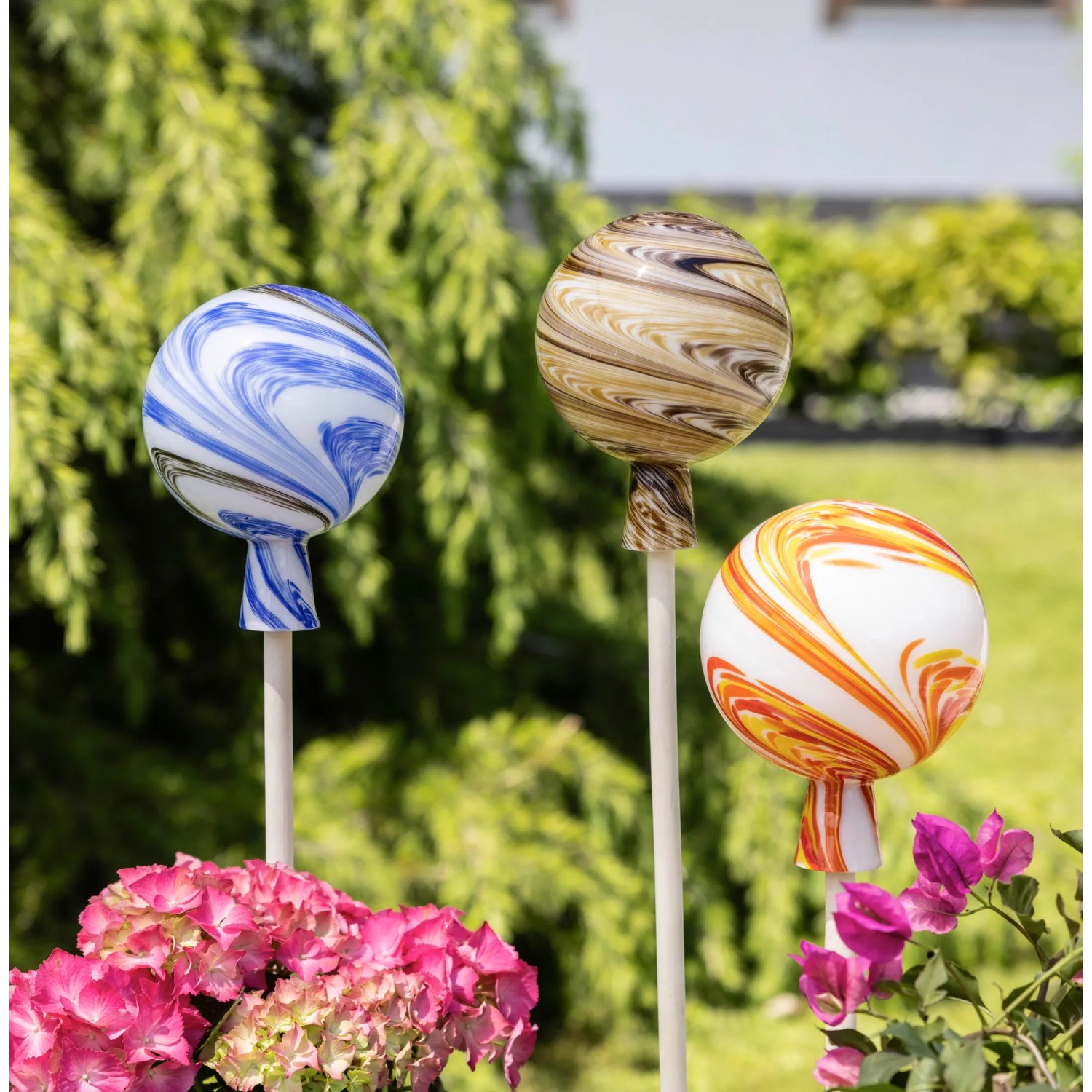 Mehrfarbige Windhager Rosenkugeln (Ø 15cm) als Gartendekoration im Beet.